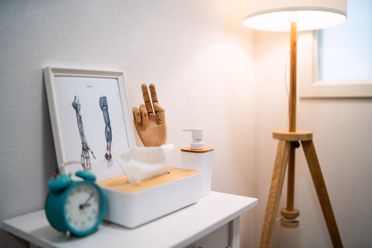 Ablage mit Anatomie-Bild, Holzhand und Wecker im Behandlungsraum