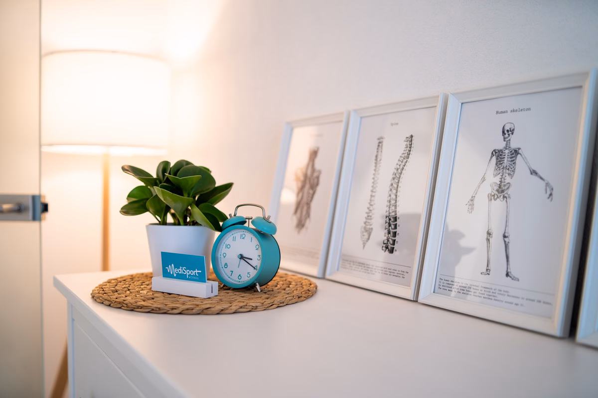 Kommode mit Anatomie-Bildern, Pflanze und Wecker