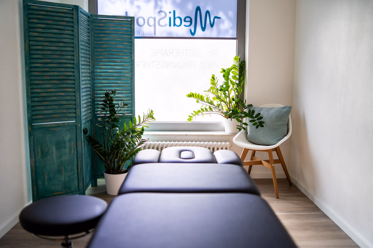 Behandlungsraum mit Therapieliege und Paravent