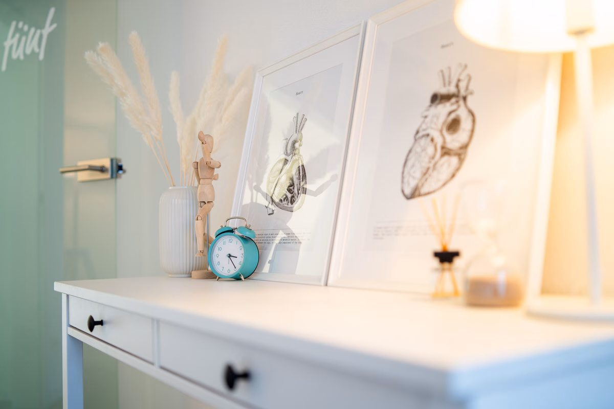 Konsole mit Anatomie-Bildern, Holzfigur und Wecker